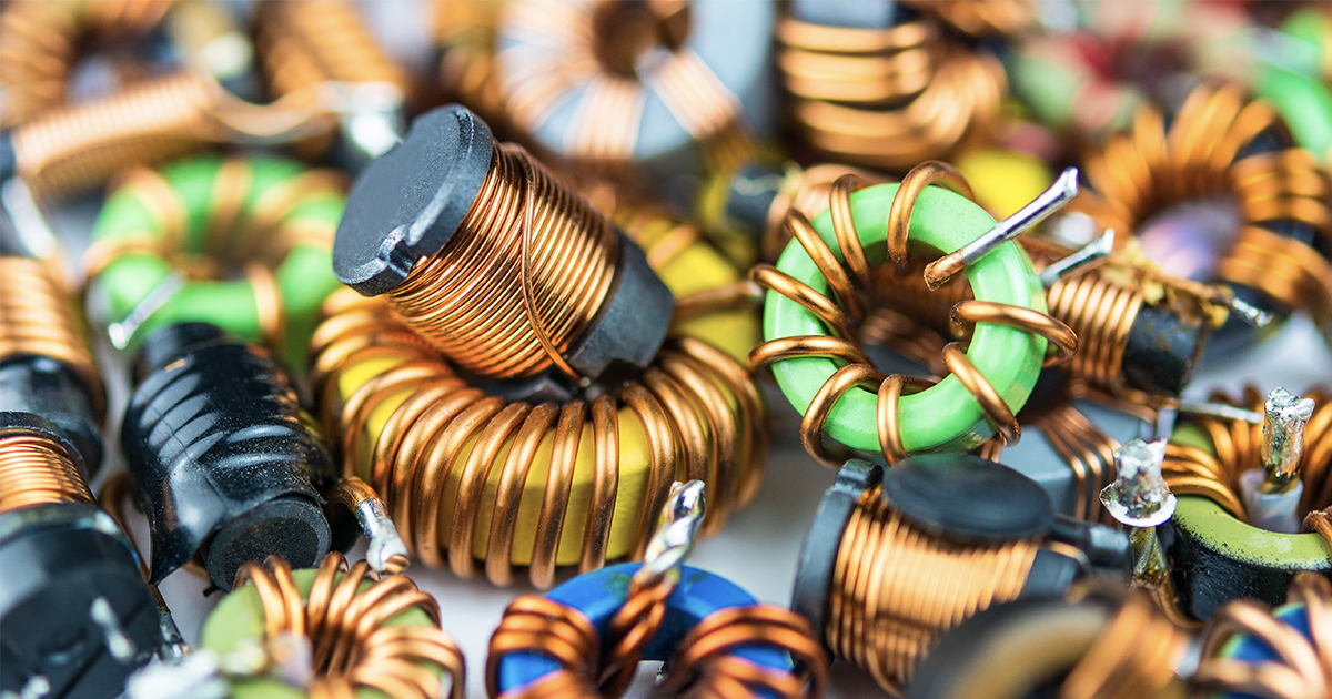 A closeup on a pile of inductors with copper winding and one with magnetic core. | Topchip